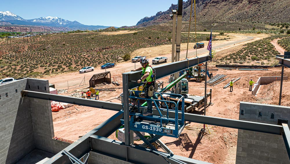 A worker with Hogan Construction secures the final support beam during construction of the Utah State University at Moab campus.