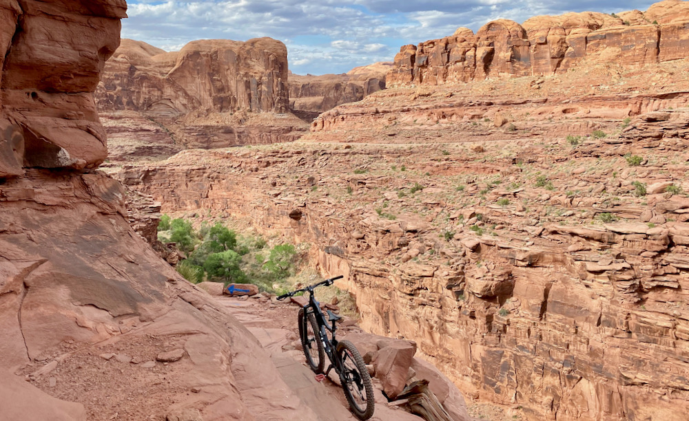 a bike stands at the ledge of a cliff along Captain Ahab, a bike trail in Moab, Utah