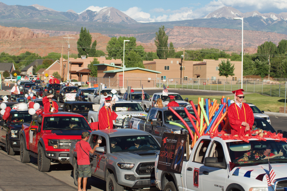 Grand County High School seniors sit atop and in their decorated vehicles, in line in front of the school during the Class of 2020 graduation ceremony