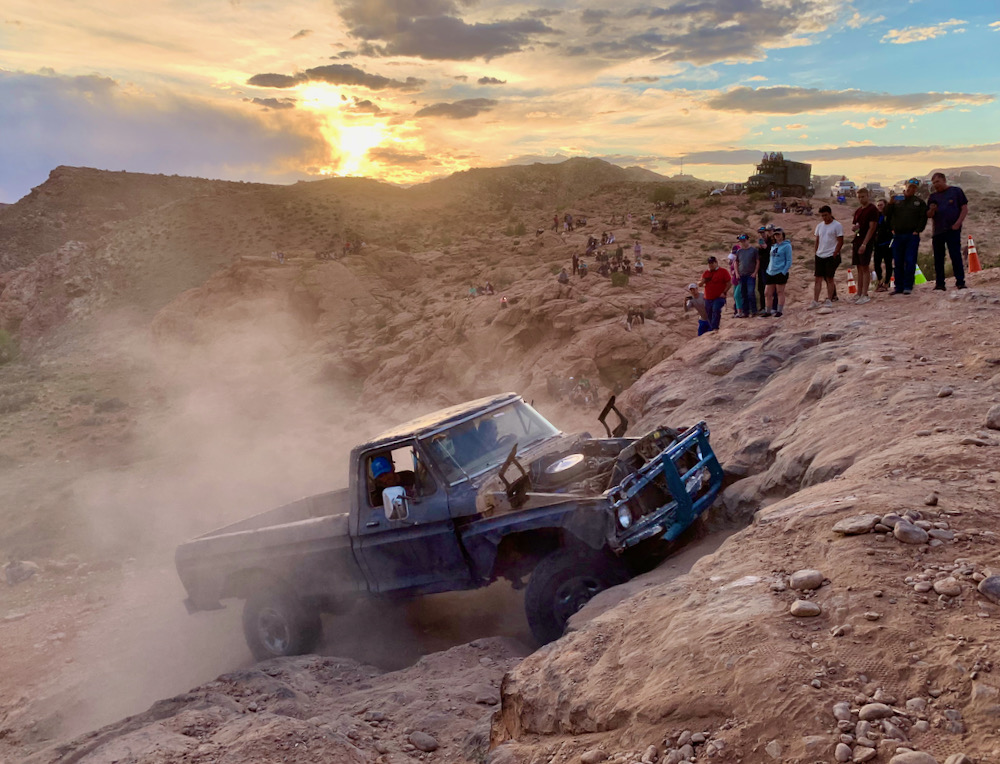an old-looking pickup truck kicks up dirt during an attempt to climb Potato Salad Hill in Moab, Utah