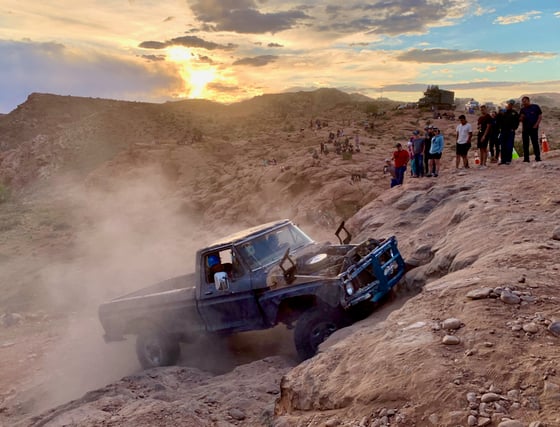 an old-looking pickup truck kicks up dirt during an attempt to climb Potato Salad Hill in Moab, Utah